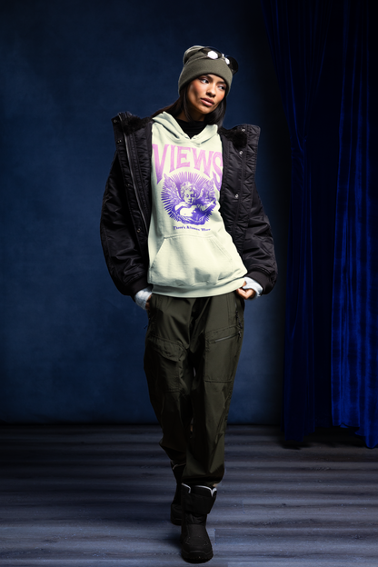 Person wearing a hoodie with 'Views' text and graphics, standing against a blue curtain.
