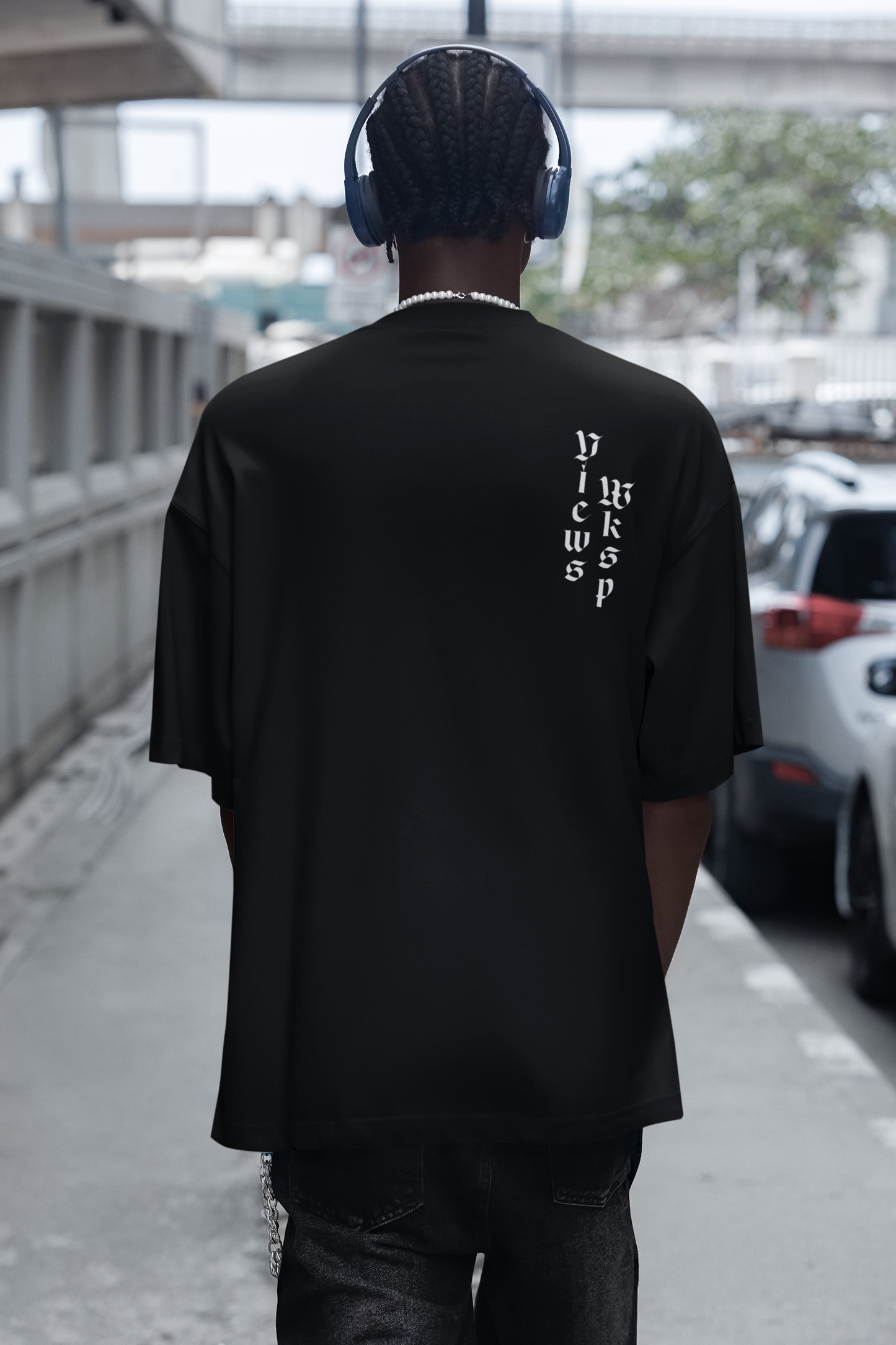 Person wearing a black t-shirt with text on the back, standing outdoors.