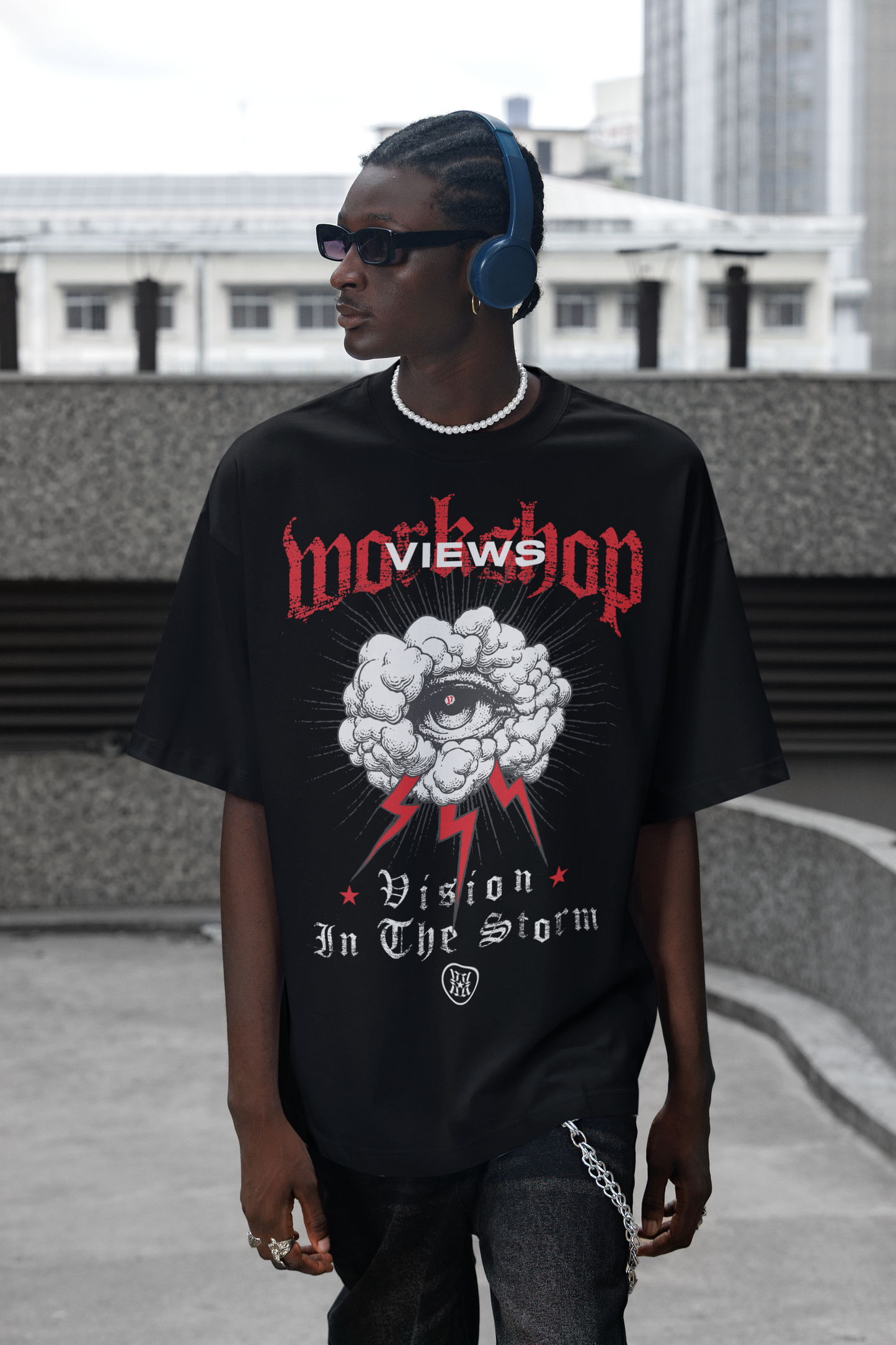 Person wearing a black t-shirt with graphic design and text, standing on a rooftop.