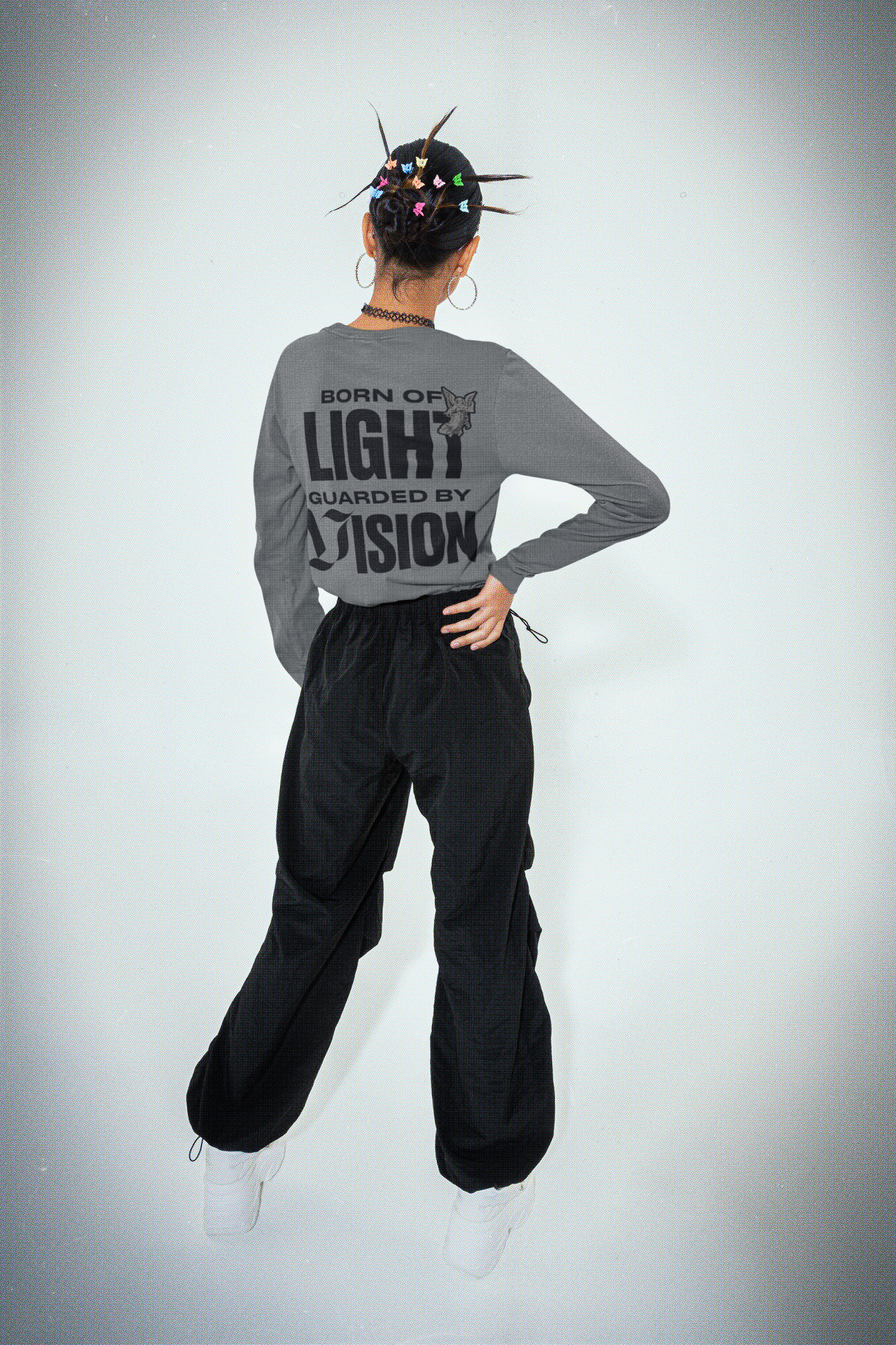 Person wearing a gray long-sleeve shirt with text and black pants on a white background