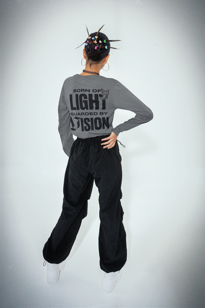 Person wearing a gray long-sleeve shirt with text and black pants on a white background