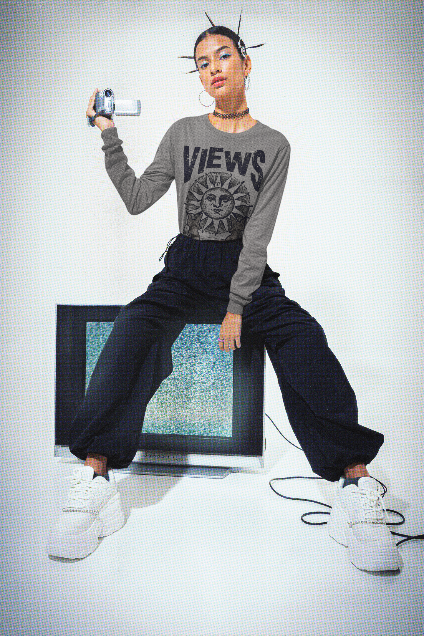 Person wearing a 'VIEWS' sweatshirt sitting on an old television set.